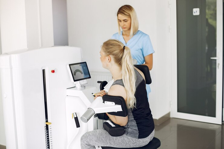 A medical professional assists a patient using rehabilitation equipment in a clinical setting.